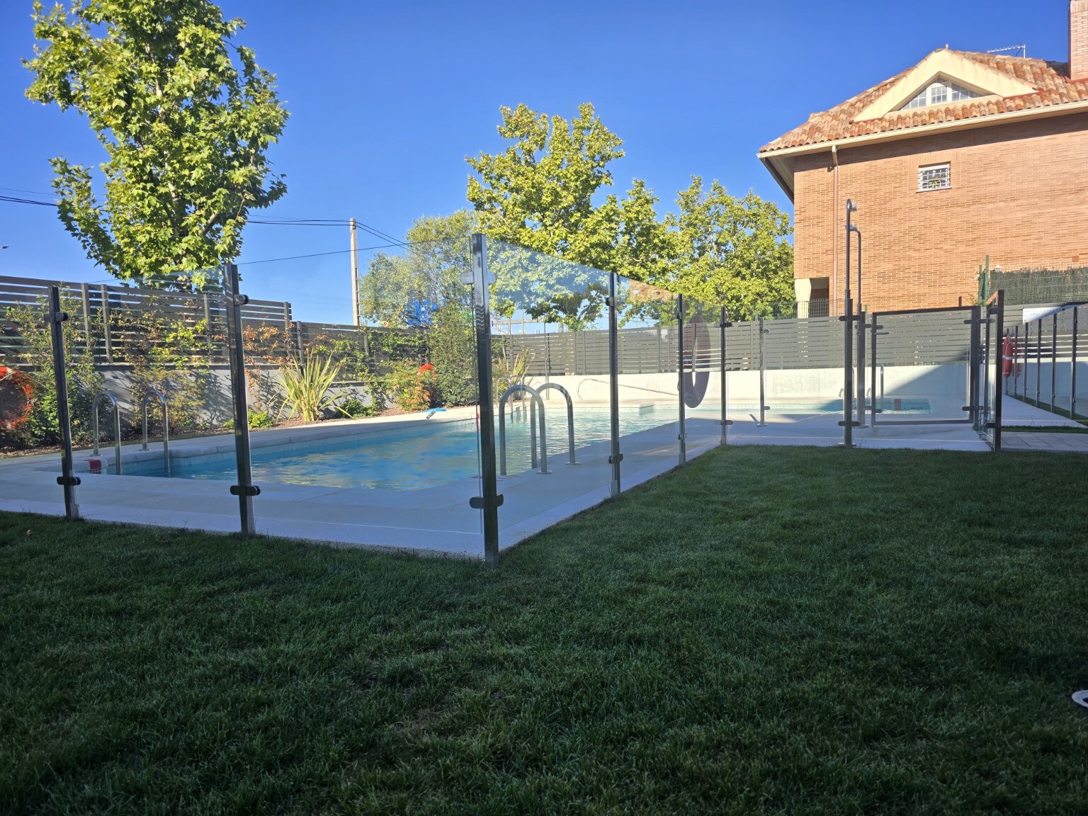 Cerramiento de vidrio transparente alrededor de una piscina comunitaria de Madrid